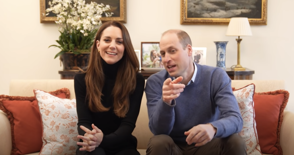 Kate Middleton & Prince William sit on a sofa laughing 