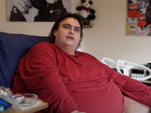 Jason Holton, Britain's fattest man, sitting on a bed