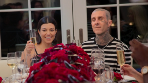 Kourtney Kardashian and Travis Barker sit at a table covered in red roses