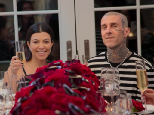 Kourtney Kardashian and Travis Barker sit at a table covered in red roses