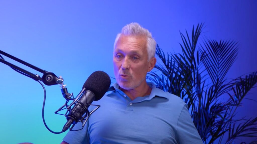 Martin Kemp sits next to a microphone wearing a blue shirt with a blue background