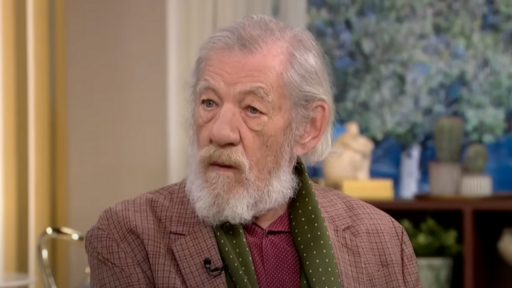 Sir Ian McKellen wears a paid jacket, green scarf and burgundy shirt