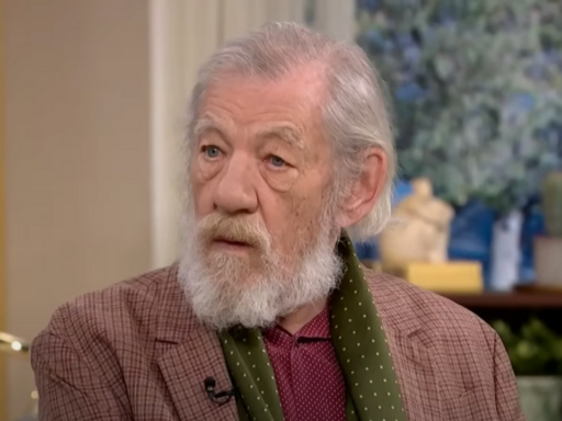 Sir Ian McKellen wears a paid jacket, green scarf and burgundy shirt